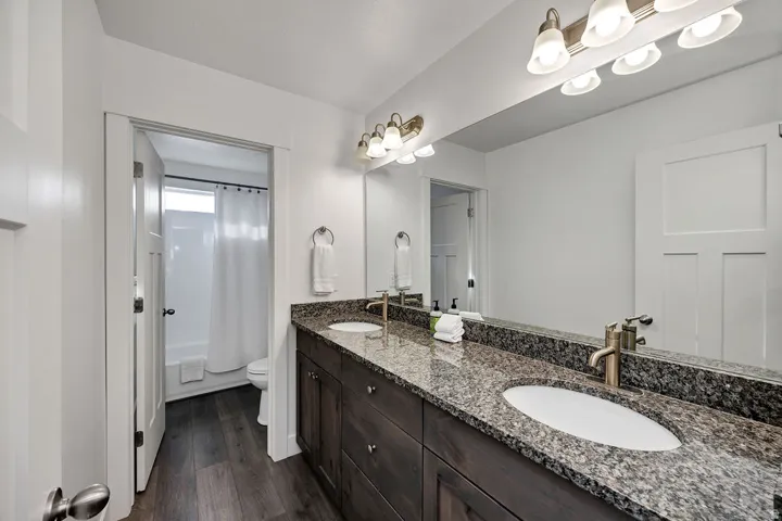 Bathroom featuring a double vanity with granite countertops, undermount sinks, and bronze-finish fixtures