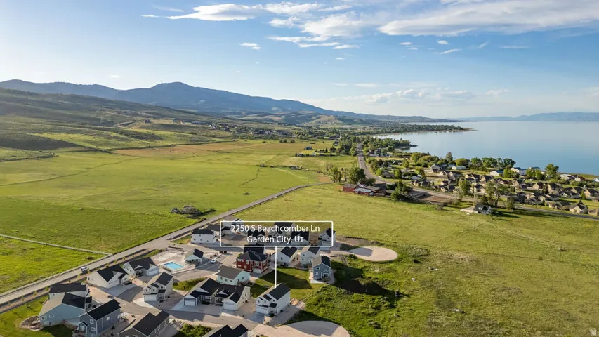 Aerial view showcasing a residential community with a large body of water and mountains in the background