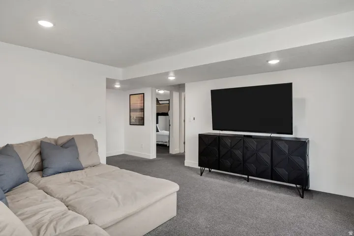 Spacious living area featuring neutral carpeting, recessed ceiling lighting, and crisp white walls