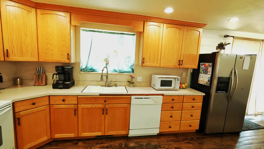 Kitchen featuring wood-finish cabinetry, light-toned countertops, and wood-finish flooring