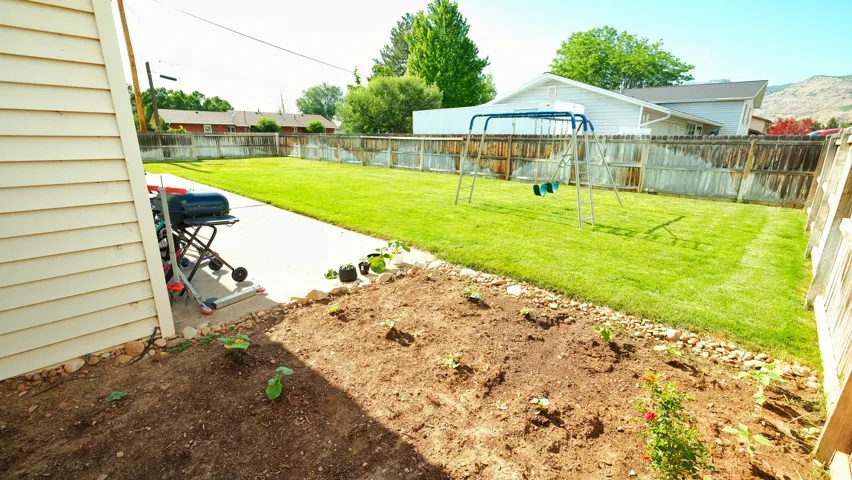 Expansive backyard featuring a manicured lawn, wood fencing, and a concrete patio