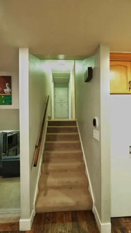 Carpeted staircase with a wood handrail and light-toned walls