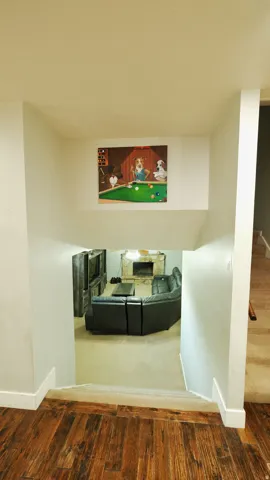 Wood-finish flooring at the top of the stairs leading to a lower-level living area