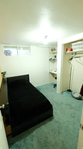 Room featuring light blue carpeting, a horizontal window, and built-in shelving