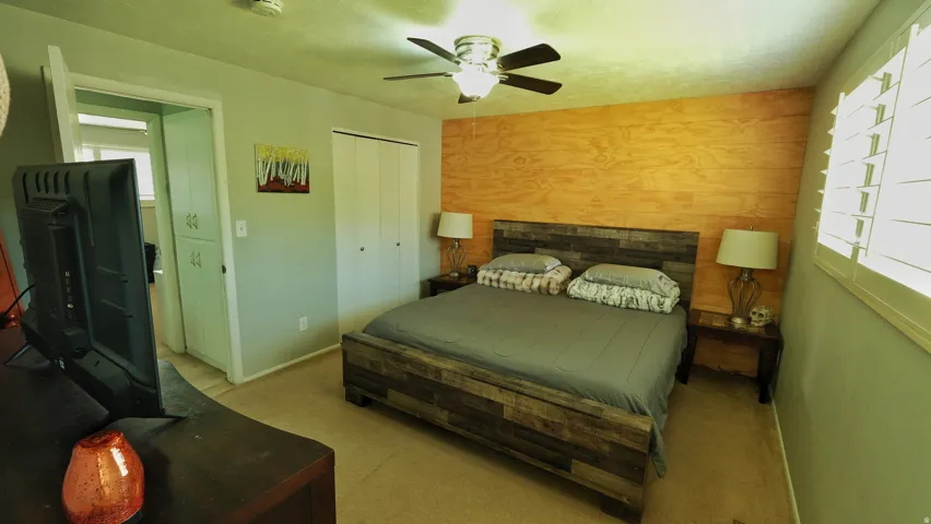 Bedroom featuring a wood-panel accent wall and ceiling fan