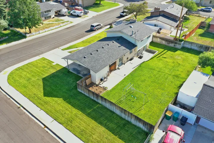 Aerial view showcasing a corner lot property with extensive green lawn areas