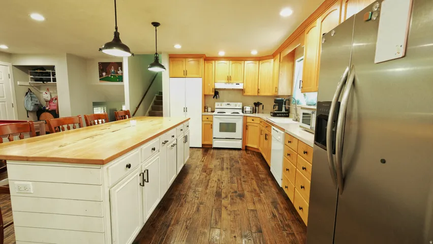 Spacious kitchen featuring a large shiplap-style island with a light wood countertop, recessed lighting, wood-finish flooring, and natural wood cabinetry