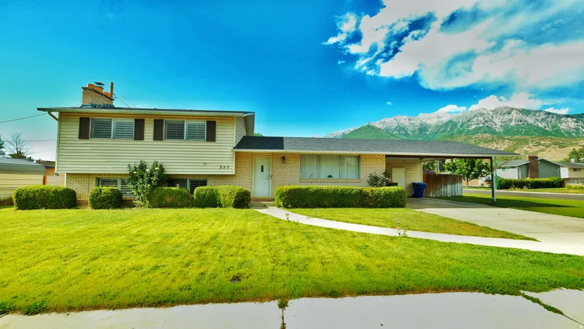 Split-level home featuring a brick and siding exterior, established front landscaping, and an attached carport