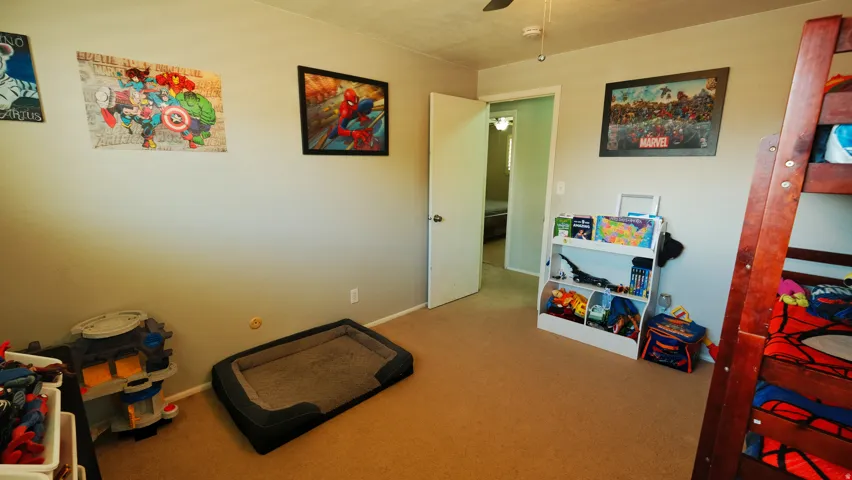 Carpeted room featuring light gray walls, white trim, and a ceiling fan