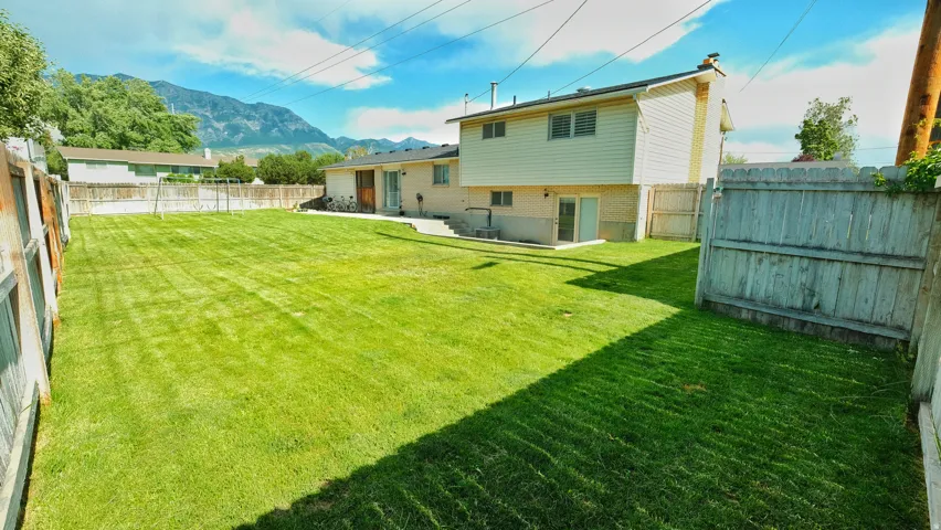 Expansive grass lawn featuring a fenced perimeter
