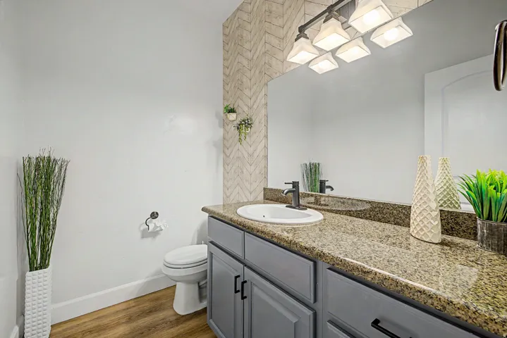 Bathroom featuring a wide vanity with a speckled countertop, a rectangular undermount sink, and a dark bronze faucet