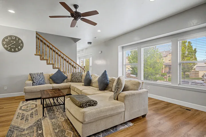 Open living area featuring wood-finish flooring, a contemporary ceiling fan, recessed lighting, and a staircase with a wooden banister