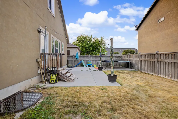 Rear exterior featuring stucco siding, a ground-level patio, and a wood fence enclosing the perimeter