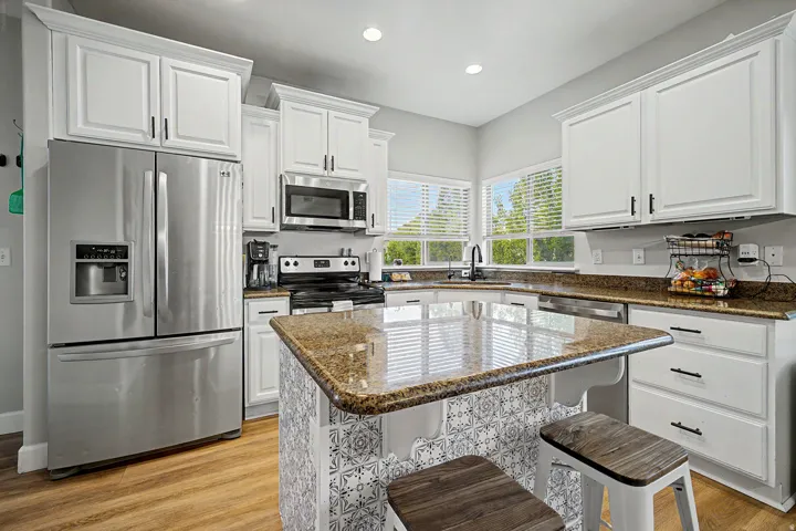 Bright kitchen featuring a central island with a patterned tile facade and an extended countertop