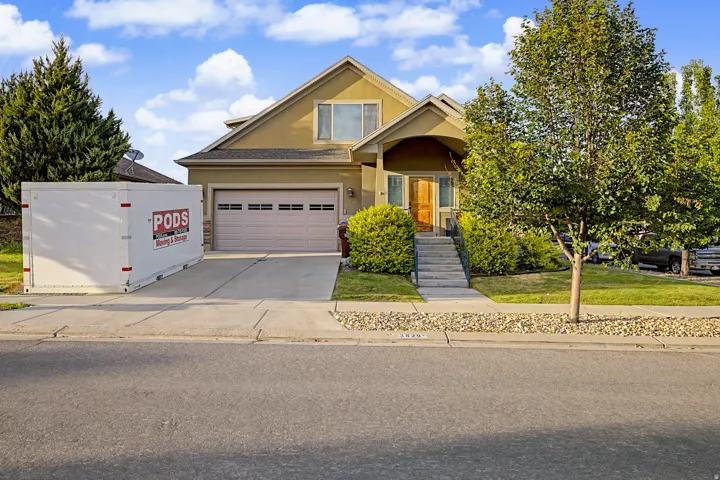 Two-story stucco home featuring an attached garage, concrete driveway, and mature landscaping