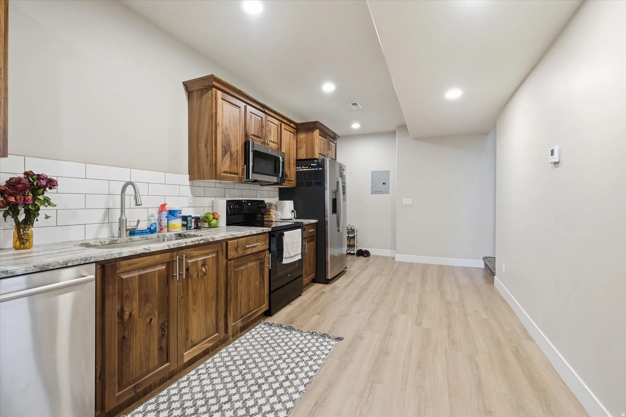 Basement ADU Full kitchen featuring wood cabinetry, white subway tile backsplash, stainless steel appliances, and stone-finish countertops