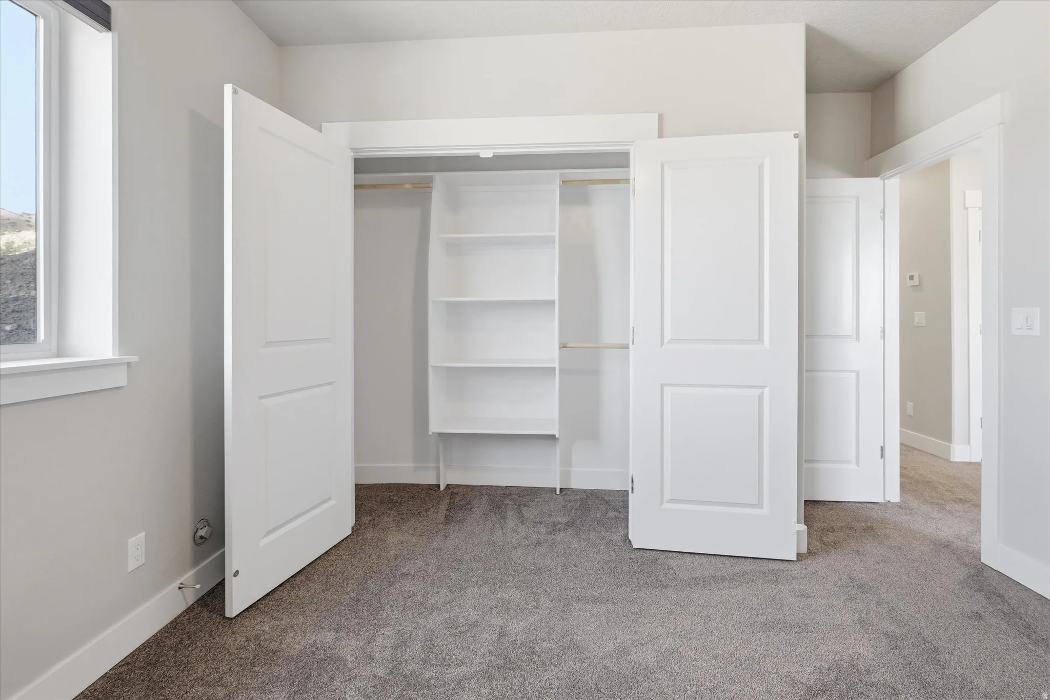 Room featuring neutral gray carpet, white trim, and a window with a dark roller shade