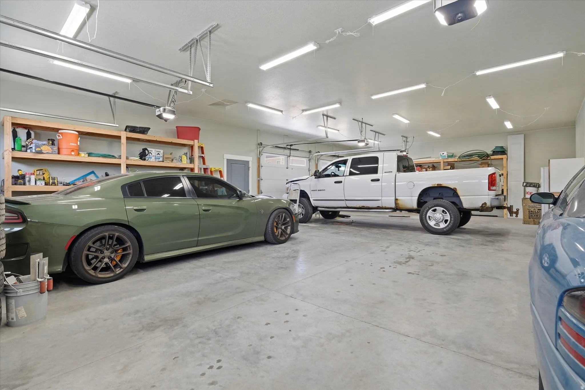 Spacious garage featuring a concrete floor, overhead fluorescent lighting, and two automatic garage door openers