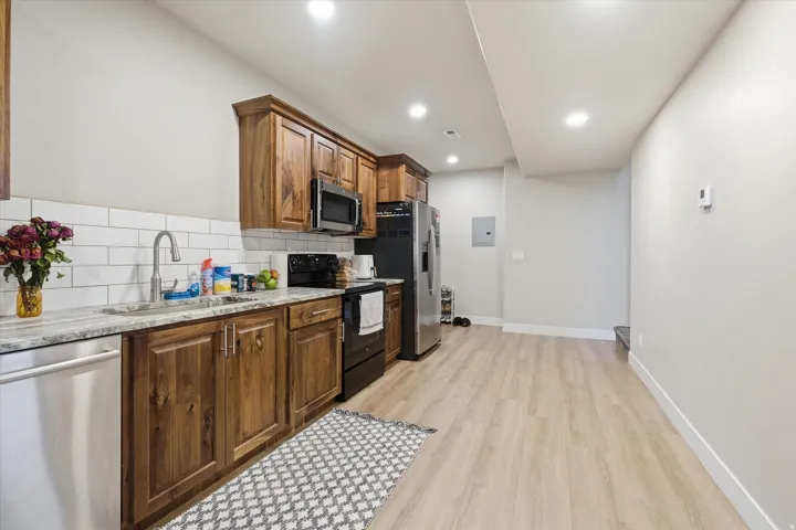 Basement ADU Full kitchen featuring wood cabinetry, white subway tile backsplash, stainless steel appliances, and stone-finish countertops