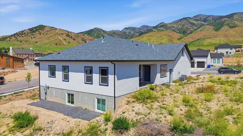 Contemporary residence featuring white stucco and exposed foundation, a dark gray shingle roof, and dark trim