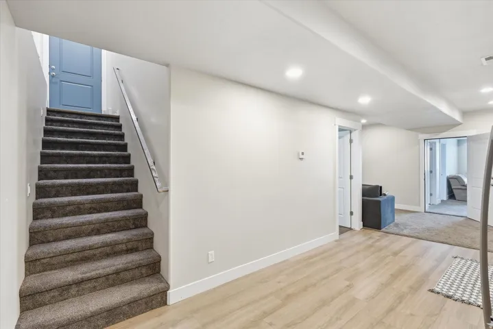 Separate basement ADU entrance.  Carpeted staircase with a modern railing leading to a blue panel door