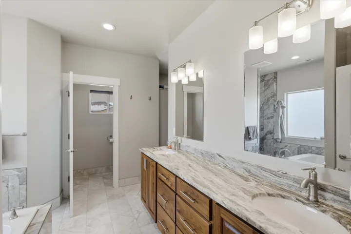 Double vanity featuring wood cabinetry and a light-toned, veined countertop