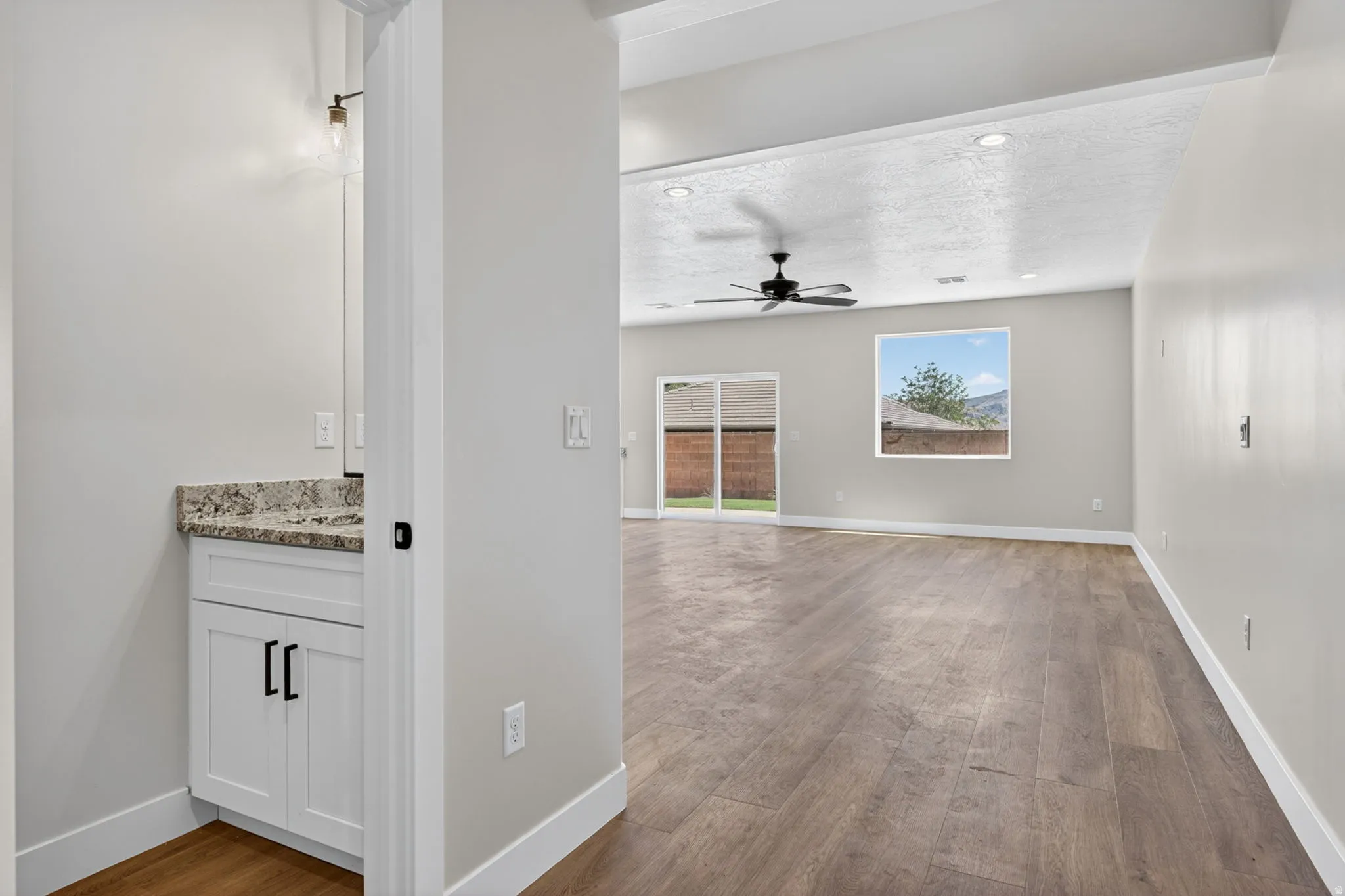 Spacious interior featuring wood-finish flooring, light gray walls, recessed lighting, and a ceiling fan