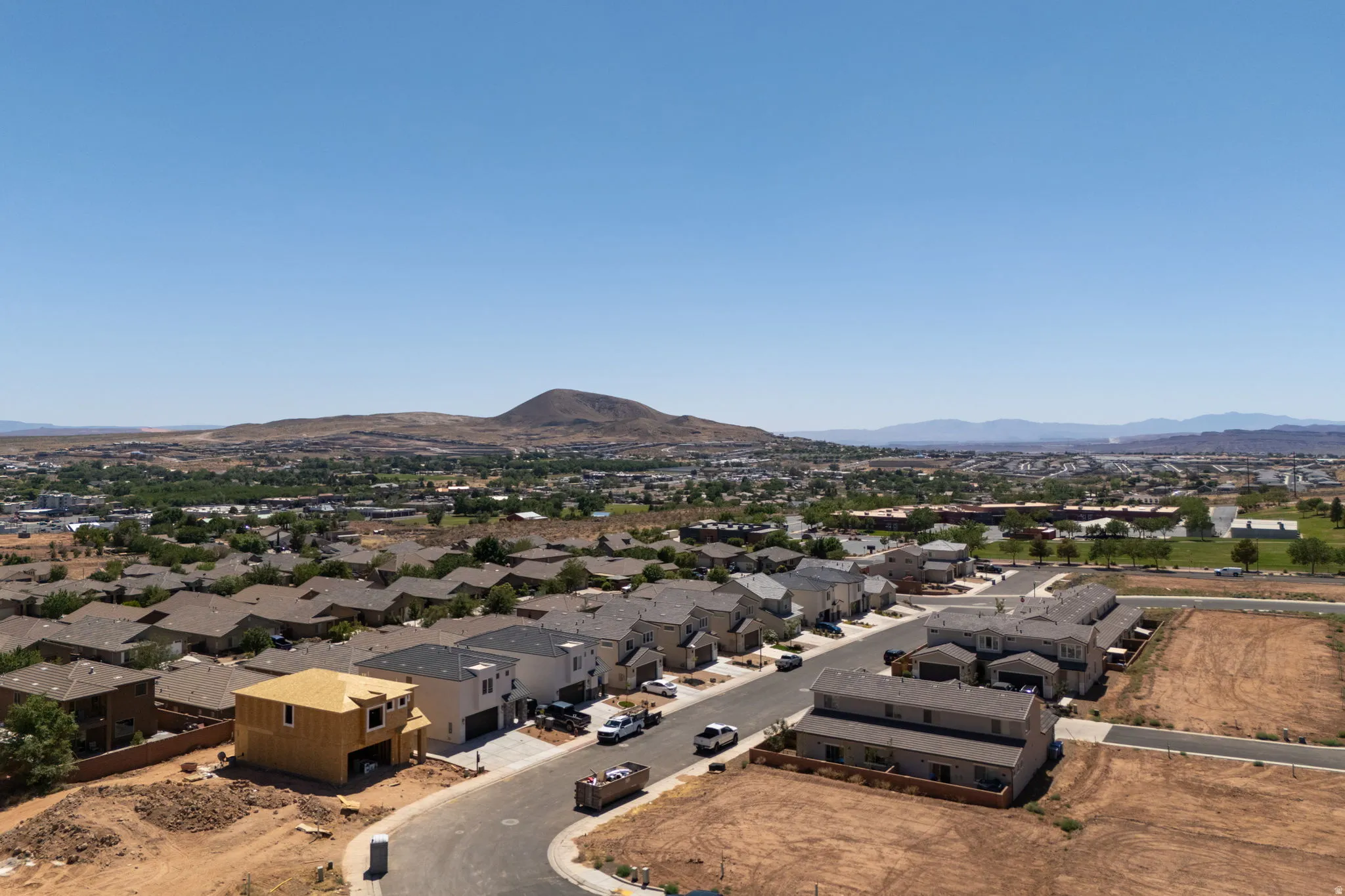 Developing residential area featuring diverse architectural styles, visible mountain backdrop, and expansive clear skies