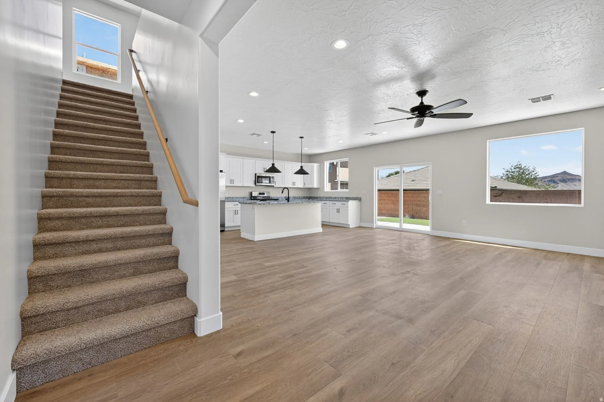 Open-concept living space featuring wood-finish flooring, a contemporary ceiling fan, and sliding glass doors to the exterior