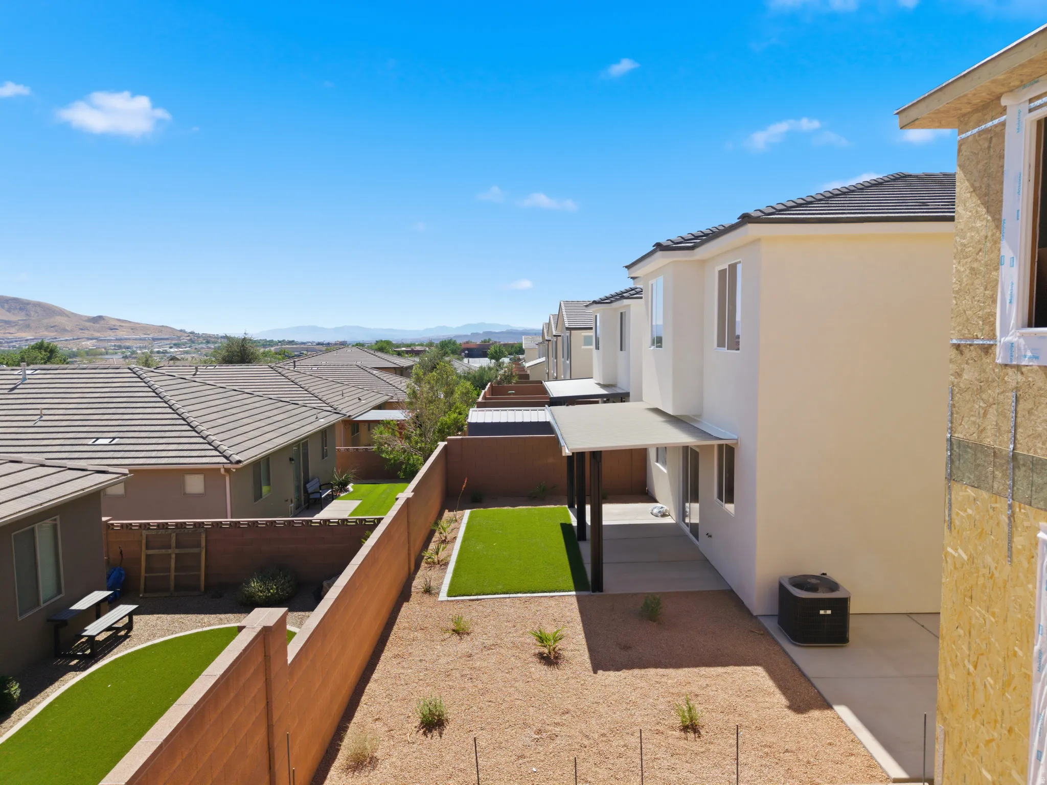 Rear exterior with covered patio, artificial turf lawn, and low-maintenance landscaping