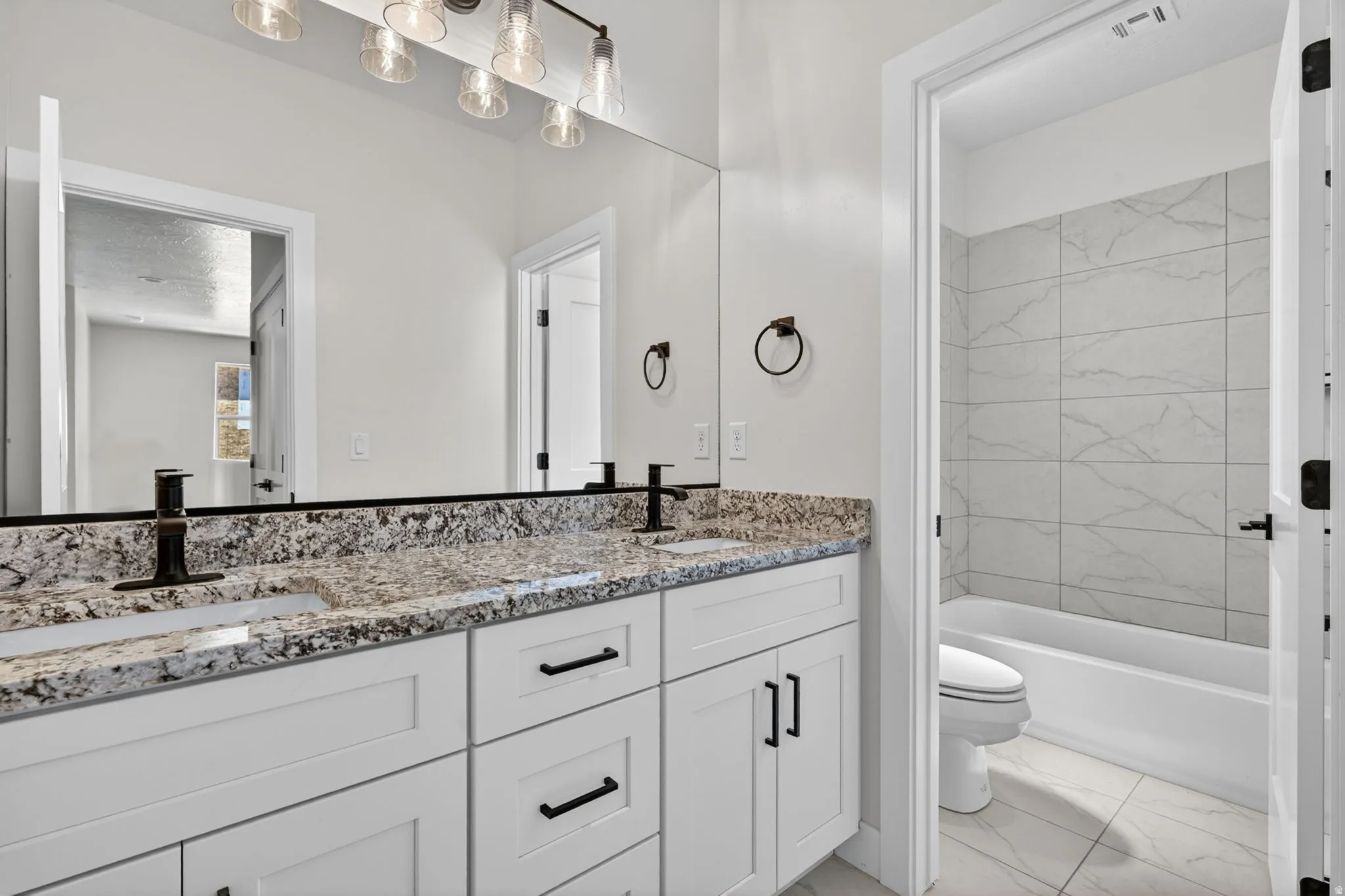 Bathroom featuring a double vanity with granite-style countertops and white cabinetry