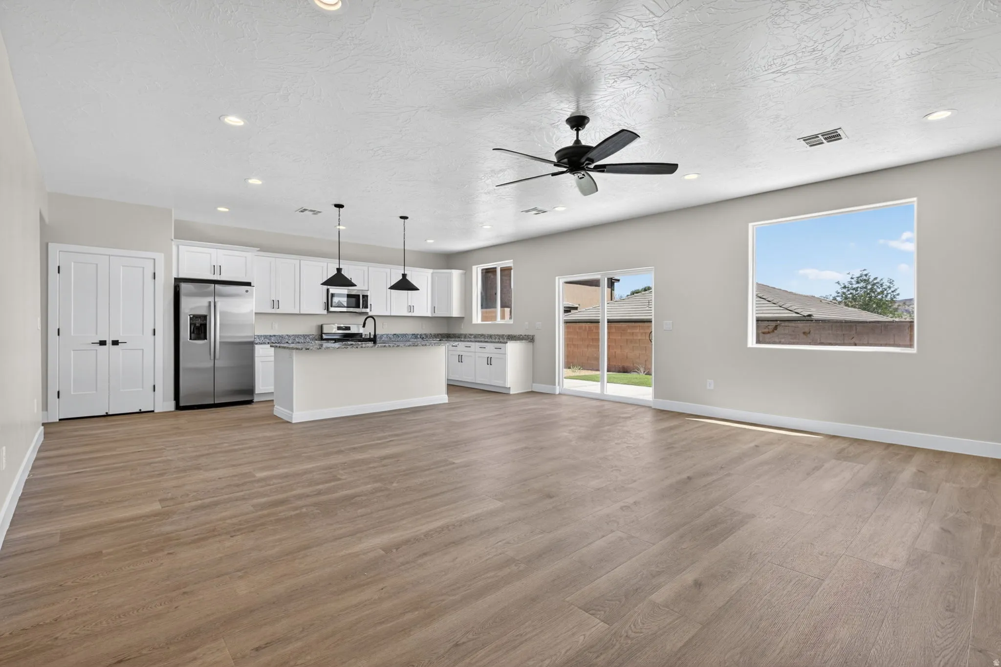 Open-concept living space featuring wood-finish flooring, recessed lighting, and a modern ceiling fan