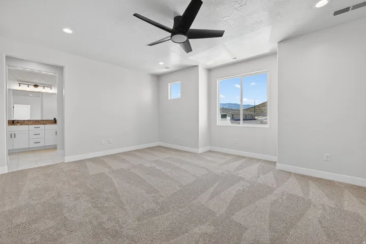 Spacious room featuring patterned carpeting, a contemporary ceiling fan, recessed lighting, and large windows with mountain scenery