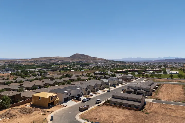 Developing residential area featuring diverse architectural styles, visible mountain backdrop, and expansive clear skies