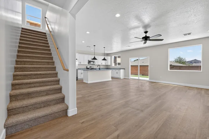 Open-concept living space featuring wood-finish flooring, a contemporary ceiling fan, and sliding glass doors to the exterior