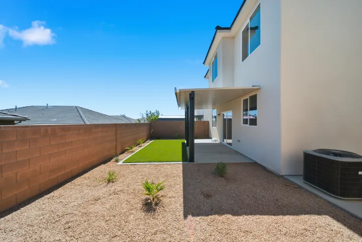 Private backyard featuring a covered patio, artificial turf, and gravel landscaping