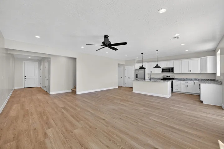 Open-concept living space with wood-finish flooring, recessed lighting, and a contemporary ceiling fan