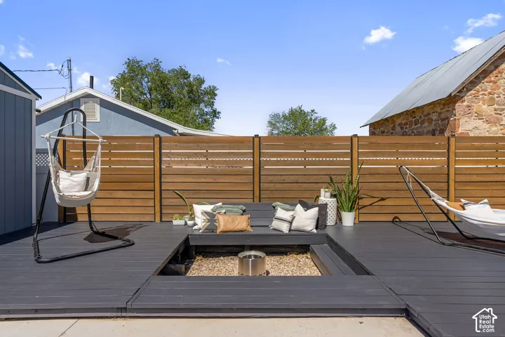 Spacious outdoor deck featuring dark-stained wood planks, built-in seating, and a central fire pit with gravel surround