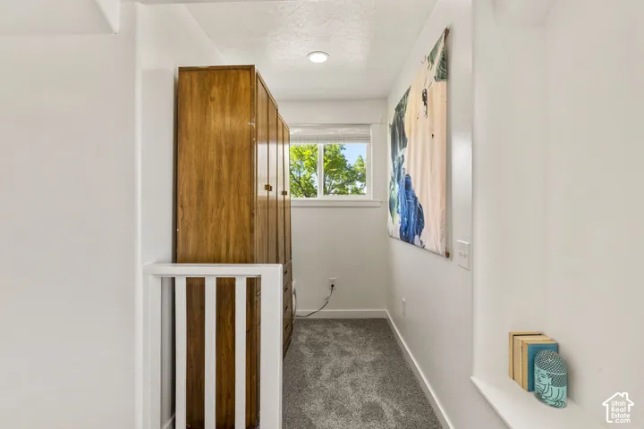 Recessed overhead lighting illuminating a hallway with light gray carpet