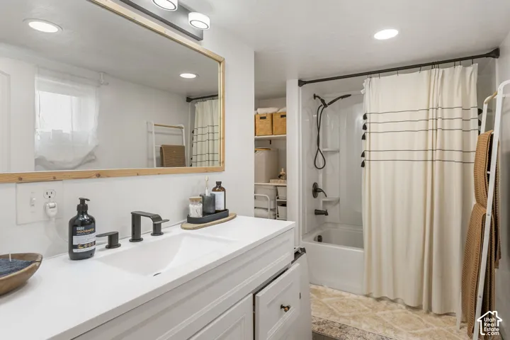 Primary bathroom featuring a white vanity with an integrated sink, matte black faucet, and a wood-framed mirror