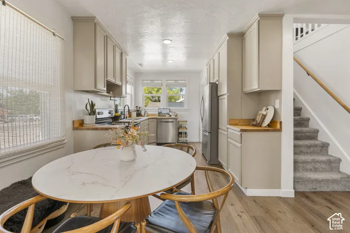 Modern kitchen featuring neutral-toned cabinetry, wood-finish countertops, stainless steel appliances, and wood-finish flooring