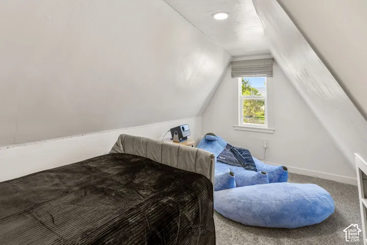 Attic room featuring sloped ceilings, recessed lighting, a single window with a fabric shade, and carpet flooring