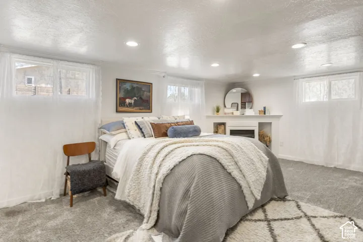Spacious primary bedroom featuring a built-in fireplace with display niches, recessed lighting, and light-colored carpeting