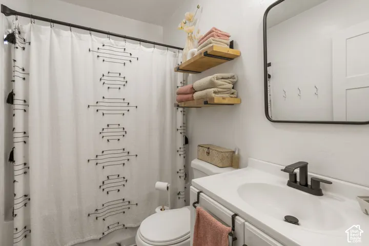 Bathroom featuring a white vanity with integrated sink, dark bronze hardware, a framed mirror, and two floating wood shelves