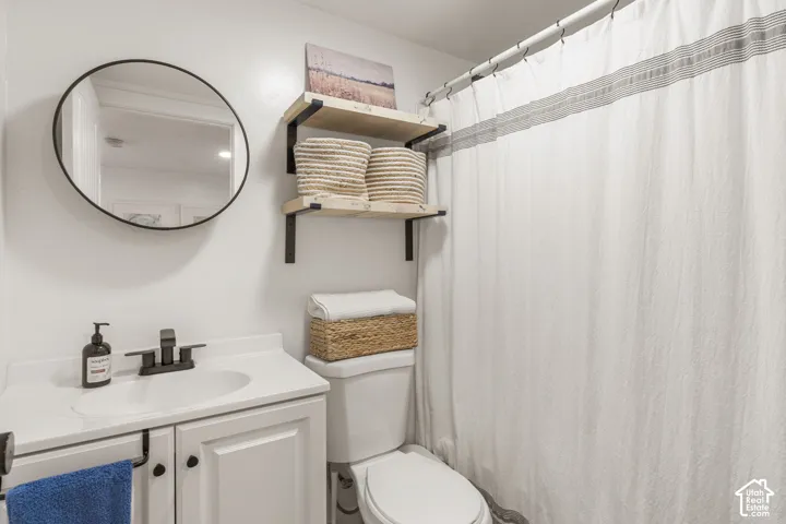 ADU bathroom featuring a white vanity with integrated sink, black-finish faucet, and coordinating round mirror