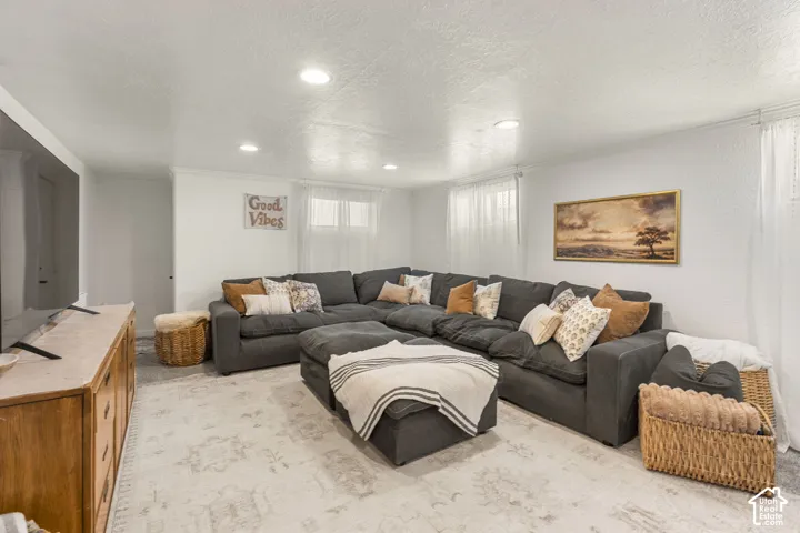 Brightly lit living space featuring recessed lighting, a light-toned area rug, white walls, and multiple windows with sheer white curtains