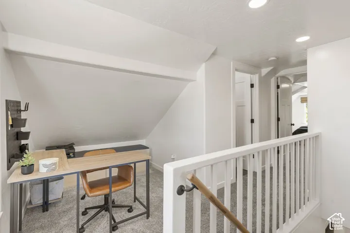 Carpeted loft area featuring recessed lighting, and a white railing with a wooden handrail