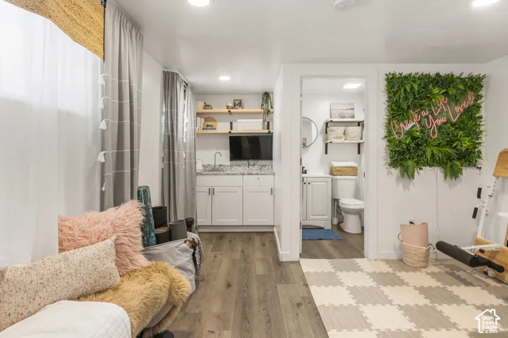 Casita featuring wood-finish flooring, recessed lighting, and a built-in wet bar with white cabinetry and a granite countertop