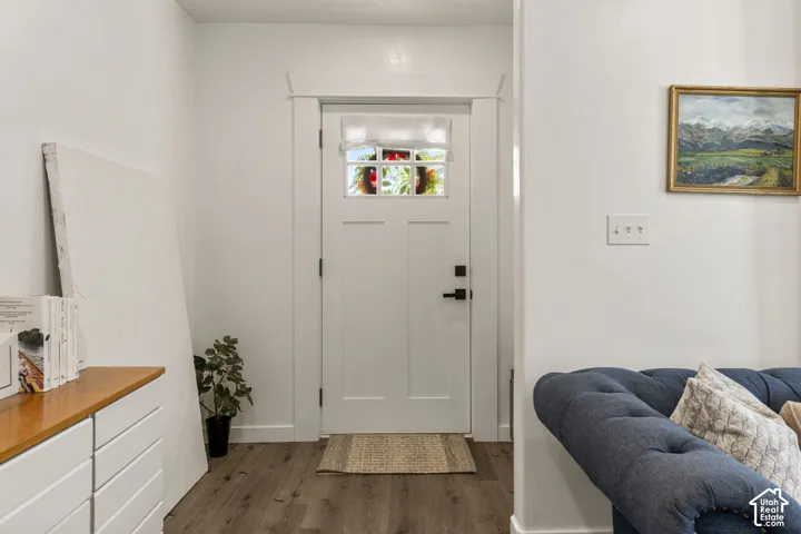 Entryway featuring a white paneled door with stained glass accents, dark hardware, and wood-finish flooring