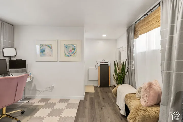 Versatile interior space featuring wood-finish flooring, recessed lighting, and a window with a woven shade and drapery